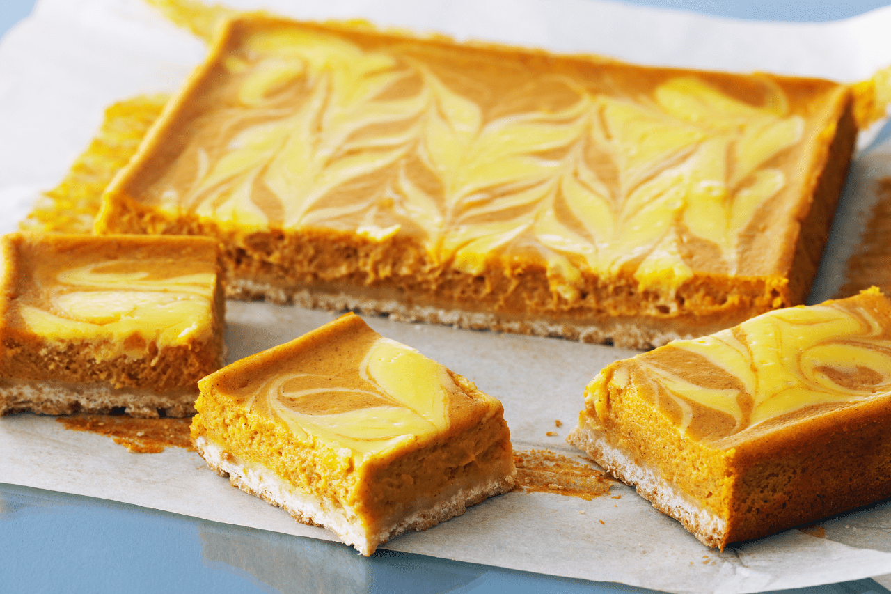 Pumpkin swirl cheesecake squares on parchment paper