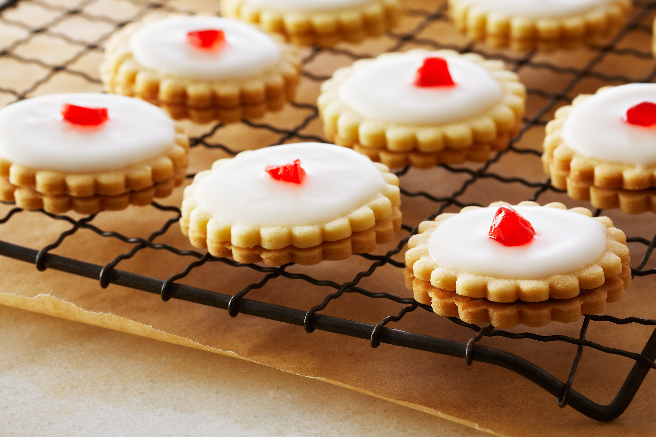 Anna Olson's empire sandwich cookies with icing cool on a black wire rack