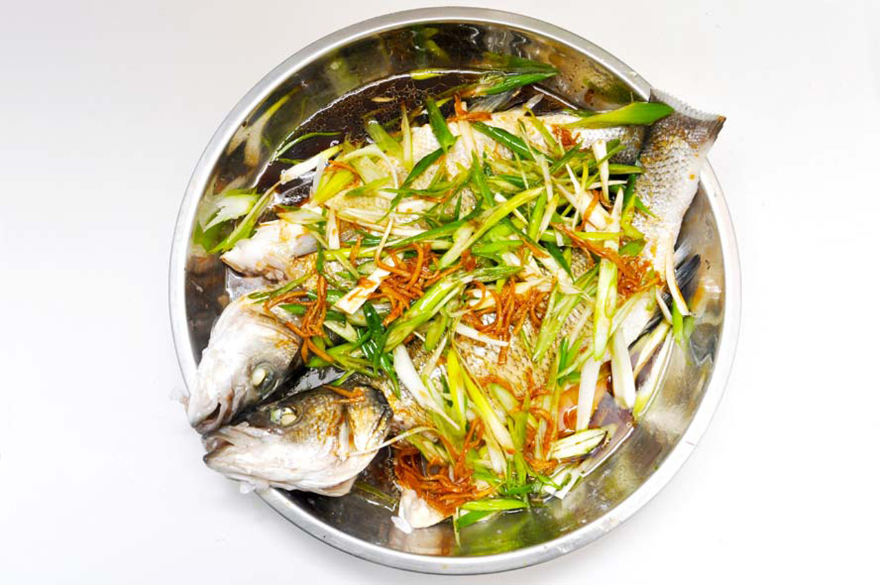 Two pieces of Chiense sea bass in an aluminum bowl