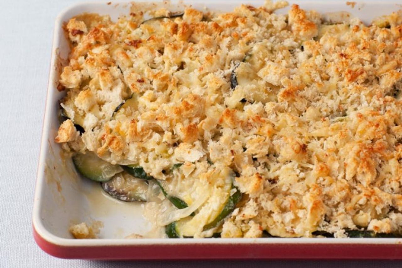 A shot of a zucchini gratin in a casserole dish with one servin g taken out