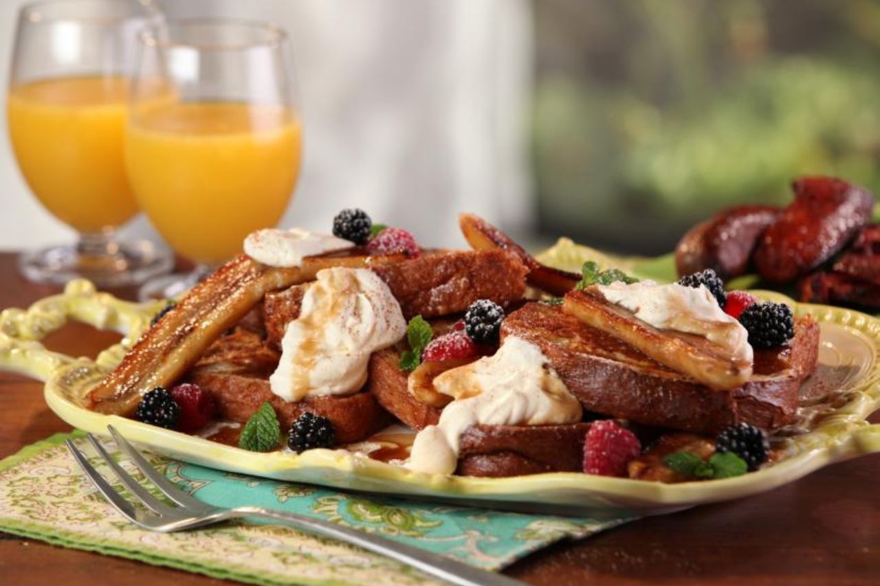 A platter of Bananas Foster French toast with whipped cream, mint and fresh berries