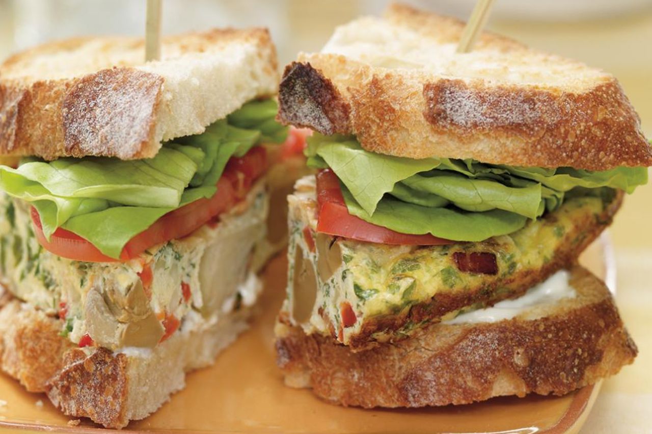 A pickled tomato sandwich with fresh tomato and lettuce on country style bread