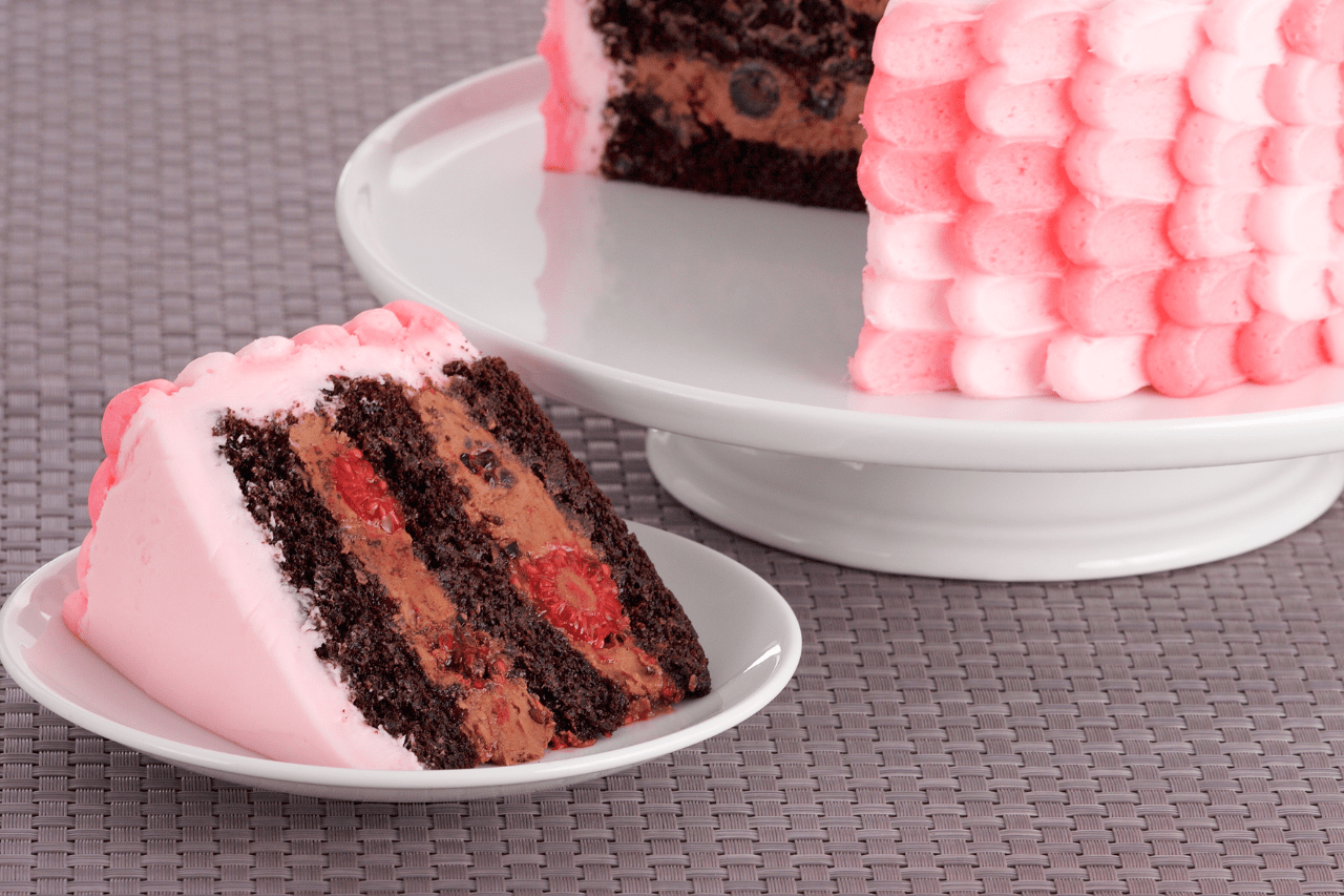 A slice of chocolate berry cake with chocolate and berry filling and a pink Italian buttercream frosting
