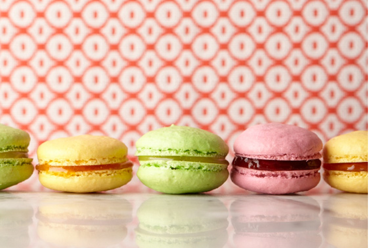 Colourful jam-filled macaron cookies sit on a countertop
