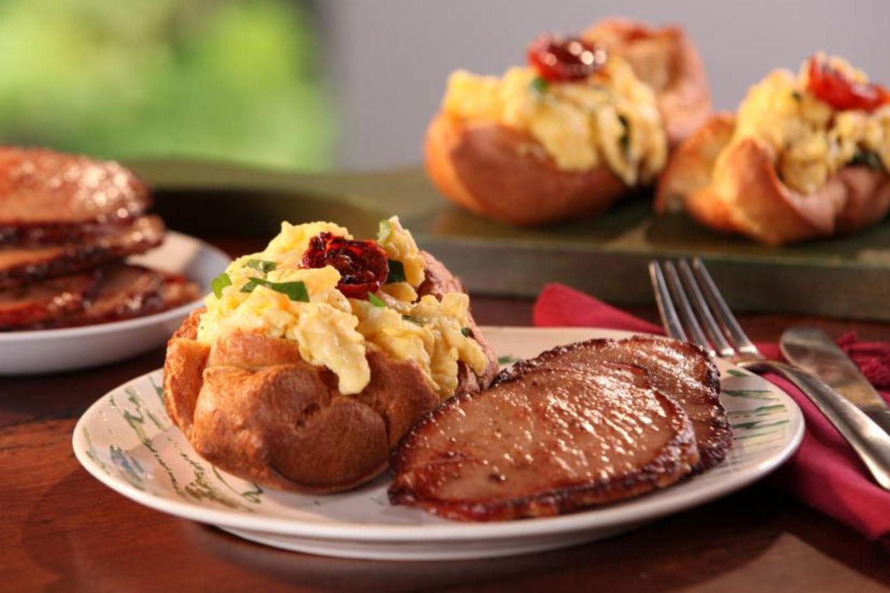 A twice-baked potato with scrambled eggs, bacon and fresh herbs beside two slices of thick-cut Canadian bacon