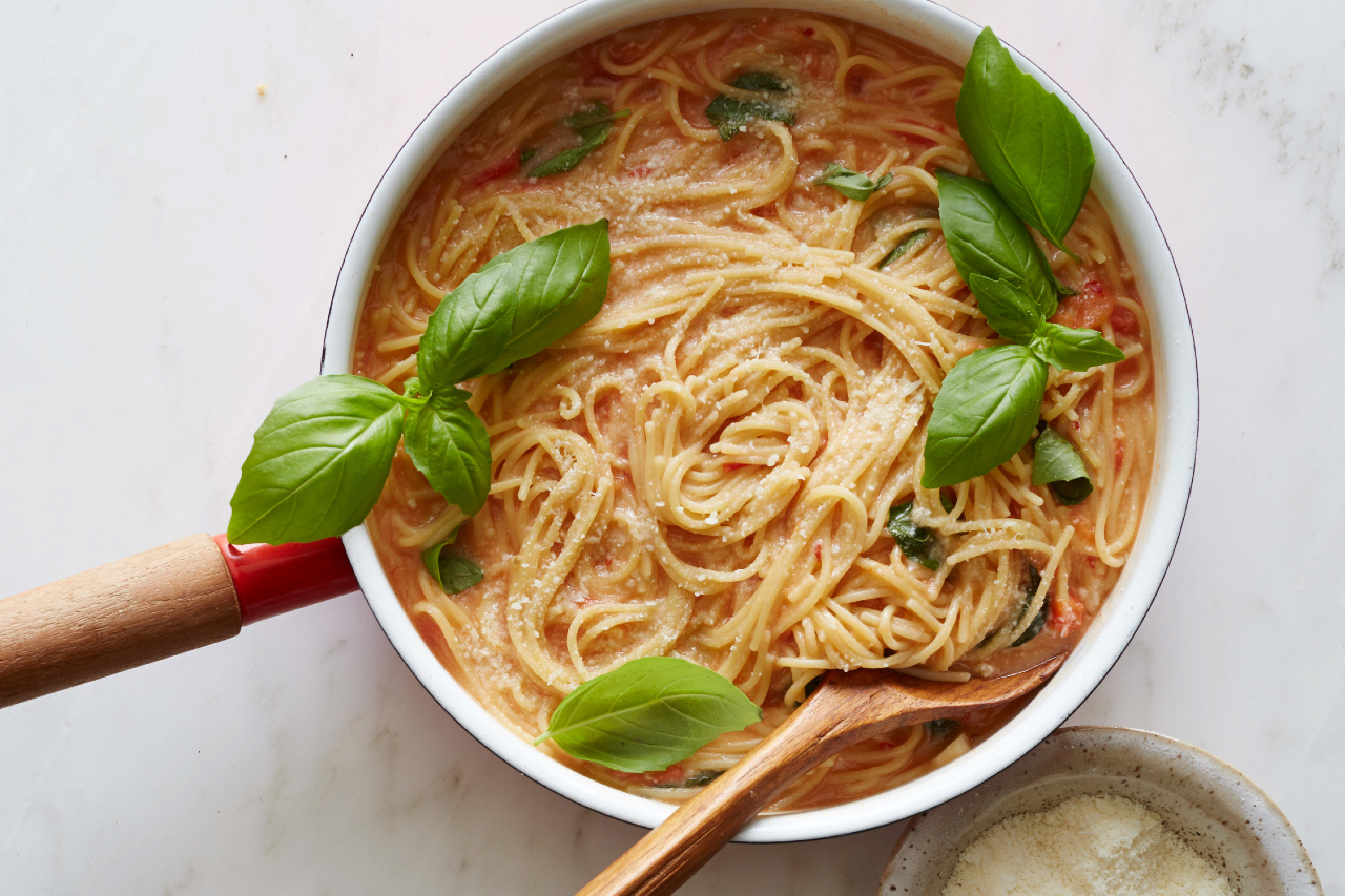 An overhead shot of one pot spaghetti with fresh tomato sauce and basil leaves