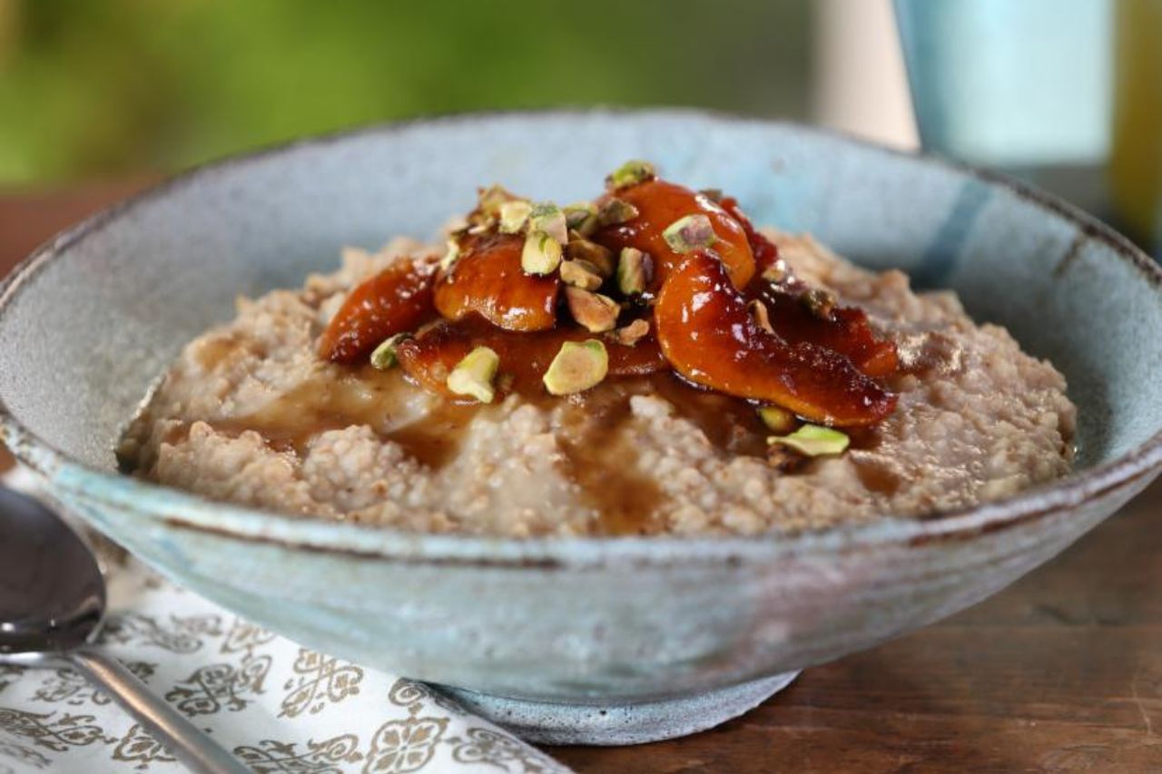 A bowl of steel-cut oatmeal topped with pistachios and apricots
