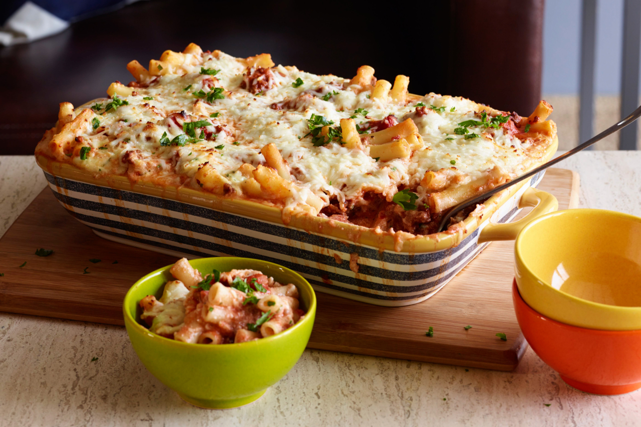 Baked ziti in a casserole dish with a bowl plated with a serving beside