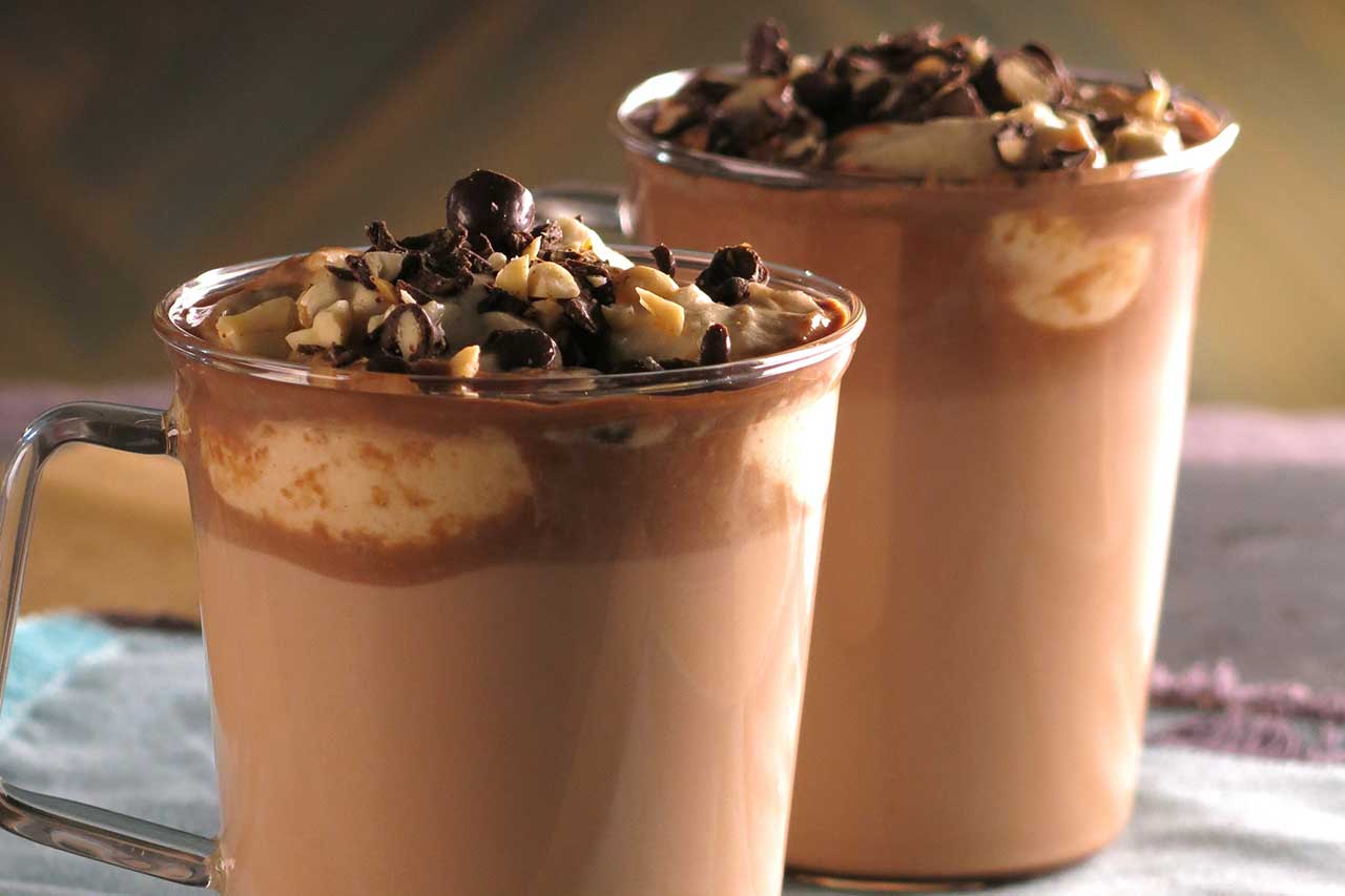 Hot chocolate topped with peanut butter whipped cream and chocolate shavings