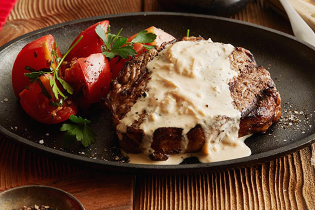 rib eye steak drizzled with cheese sauce on a plate