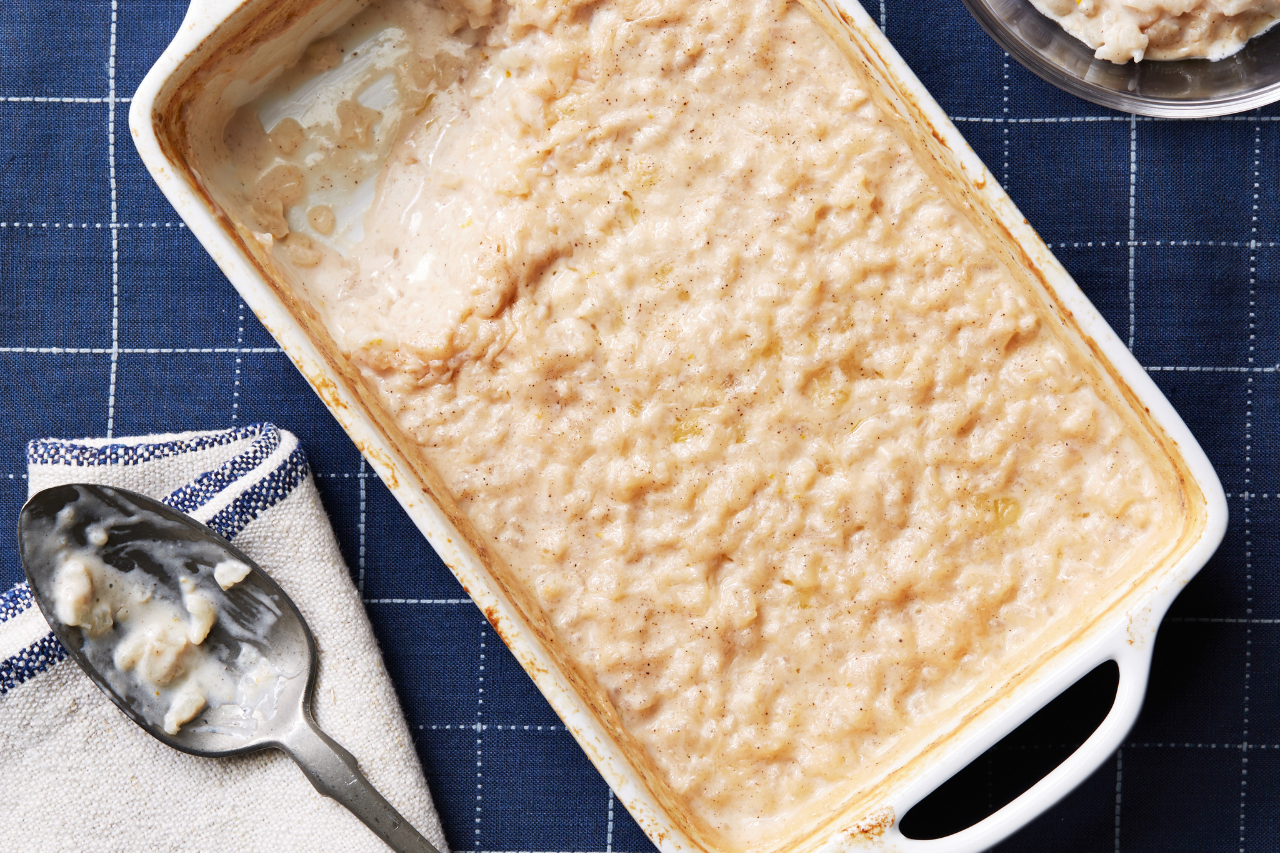 A baking dish with rice pudding topped with cinnamon, one serving scooped out