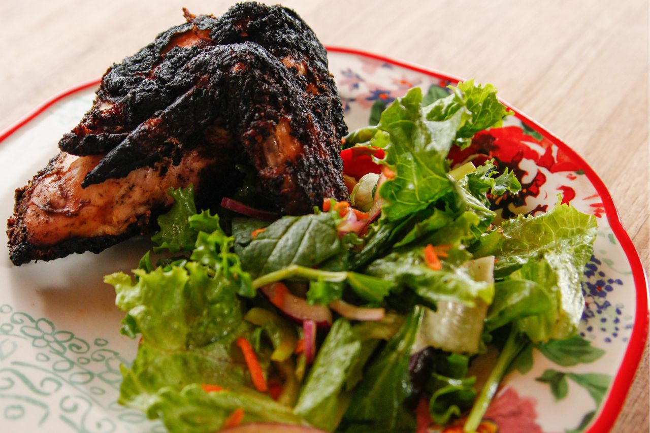 piece of jerk chicken and salad on a plate
