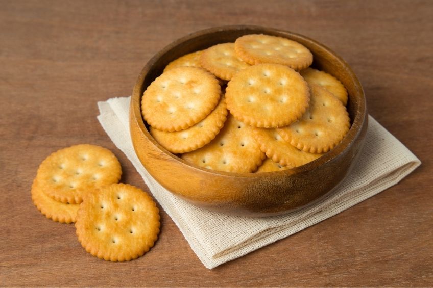 A brown bowl full of plain crackers