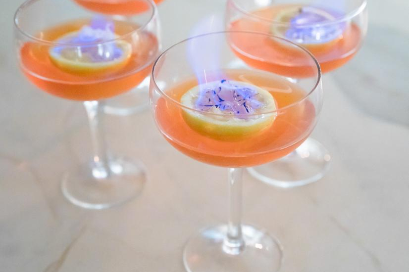 Shot of orange cocktail with flaming citrus