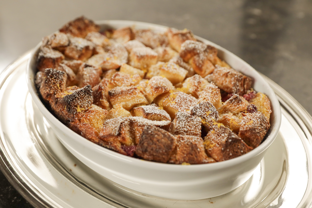 An oval casserole dish with a raspberry French toast topped with icing sugar
