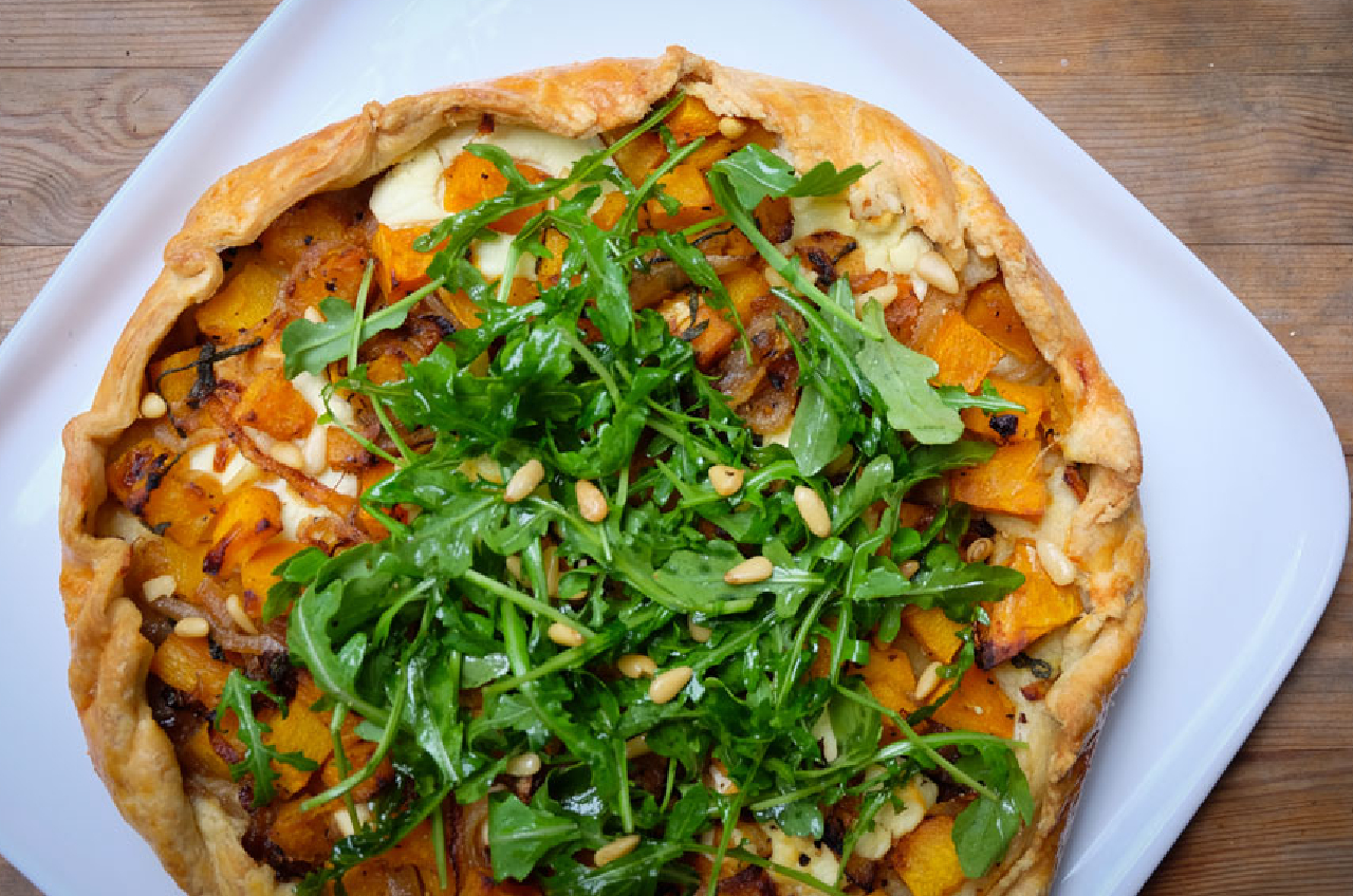 An overhead shot of a galette with roasted sweet potato and arugula