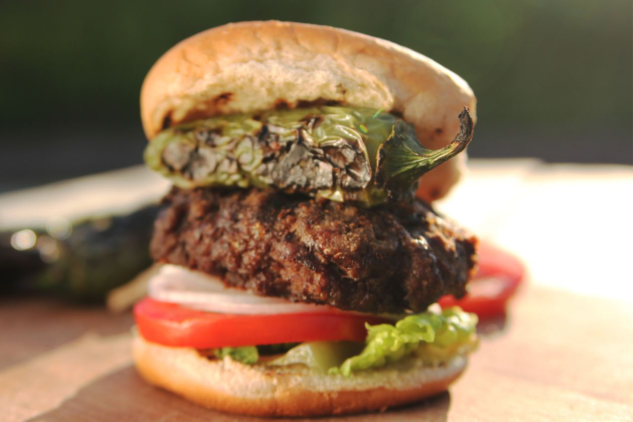 close-up of a burger with tomatoes and jalapeno