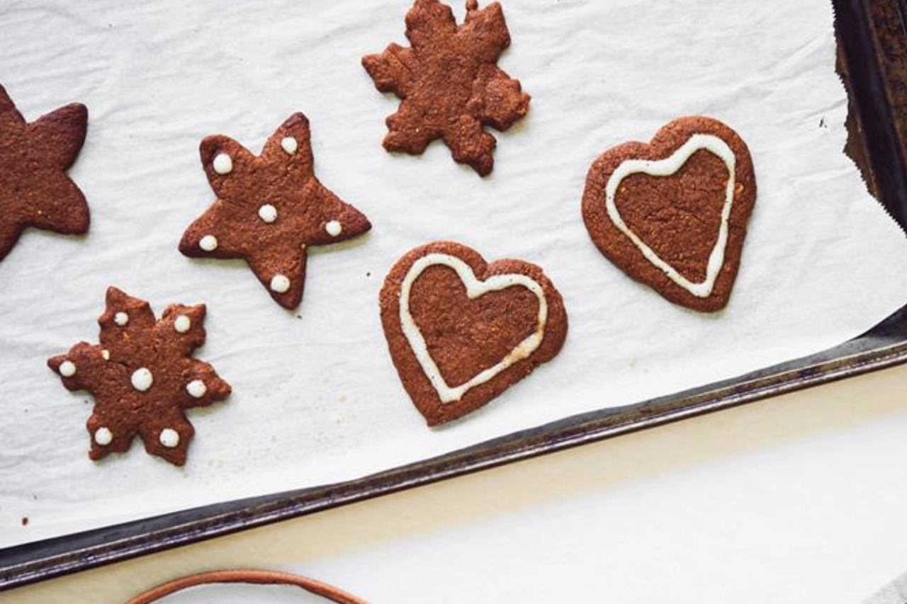 Vegan gingerbread cookies that have been frosted cool on a parchment-lined cookie tray