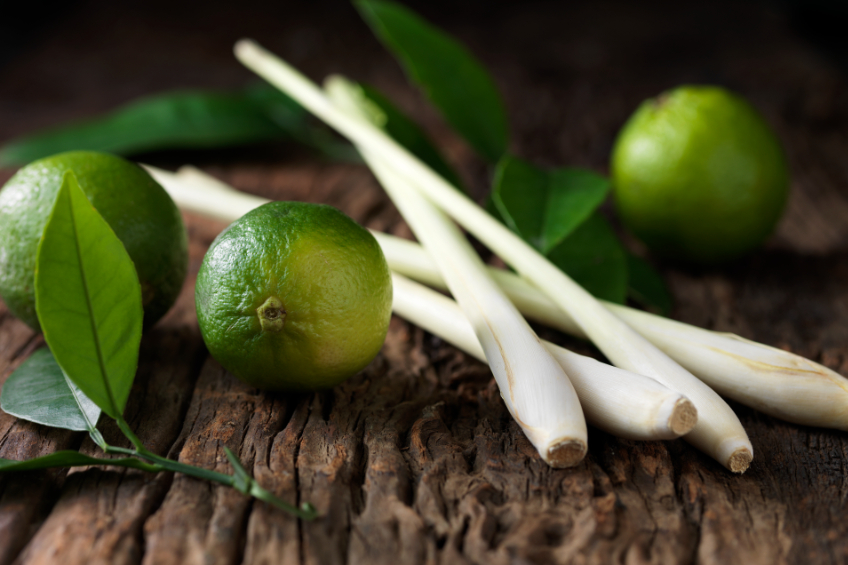Limes and lemon grass on rough wood surface - stock photo