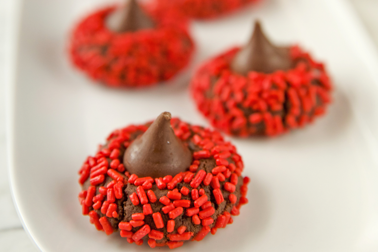 Chocolate cookies topped with red sprinkles and a chocolate kiss