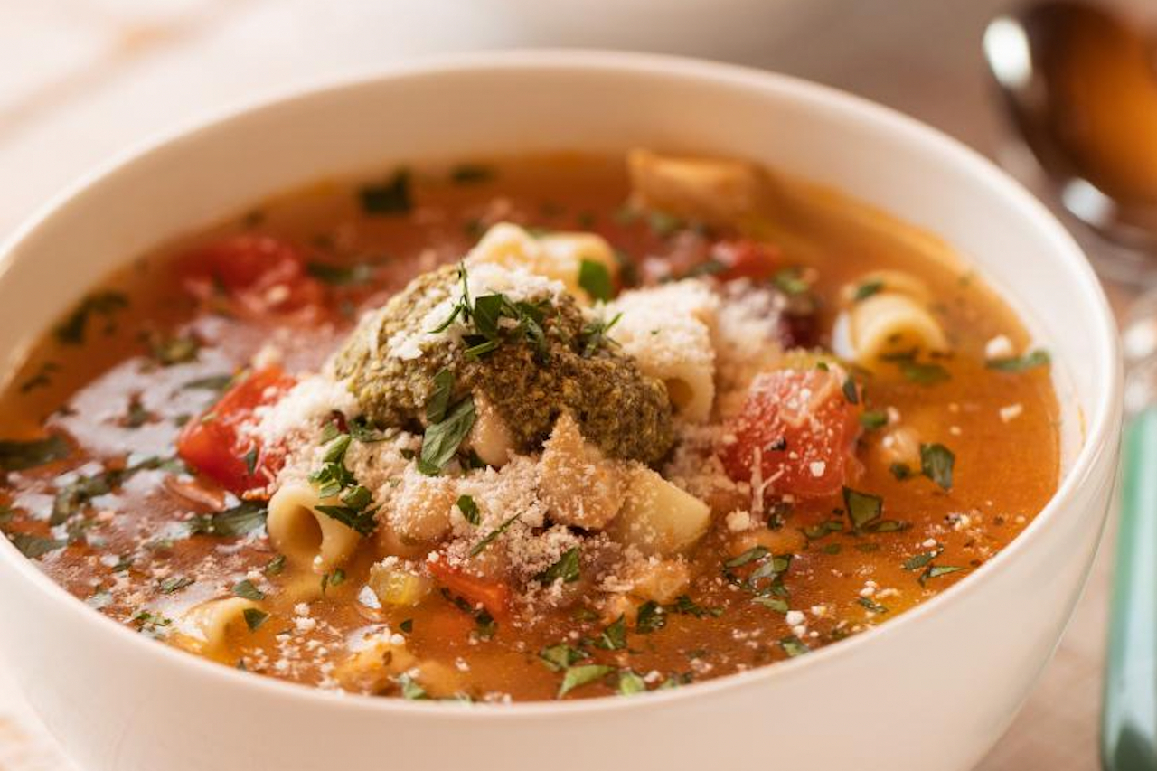 A minestrone soup topped with chicken, beans and chilli flakes