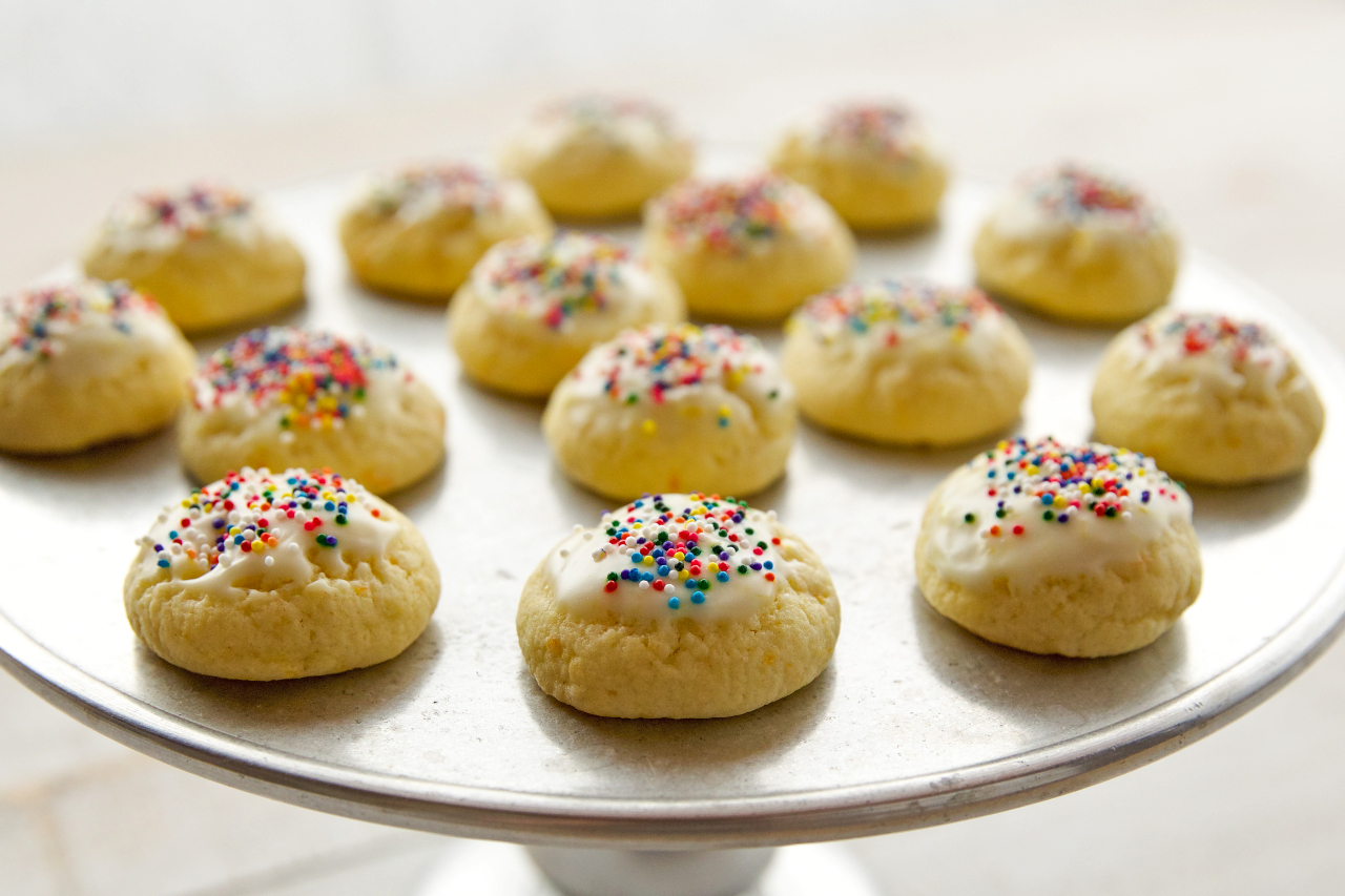 A tray of cookies with icing and colourful sprinkles