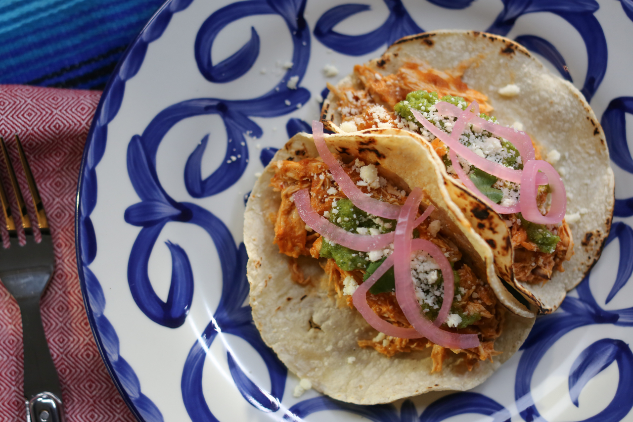Two chicken tacos with pickled red onions on a plate