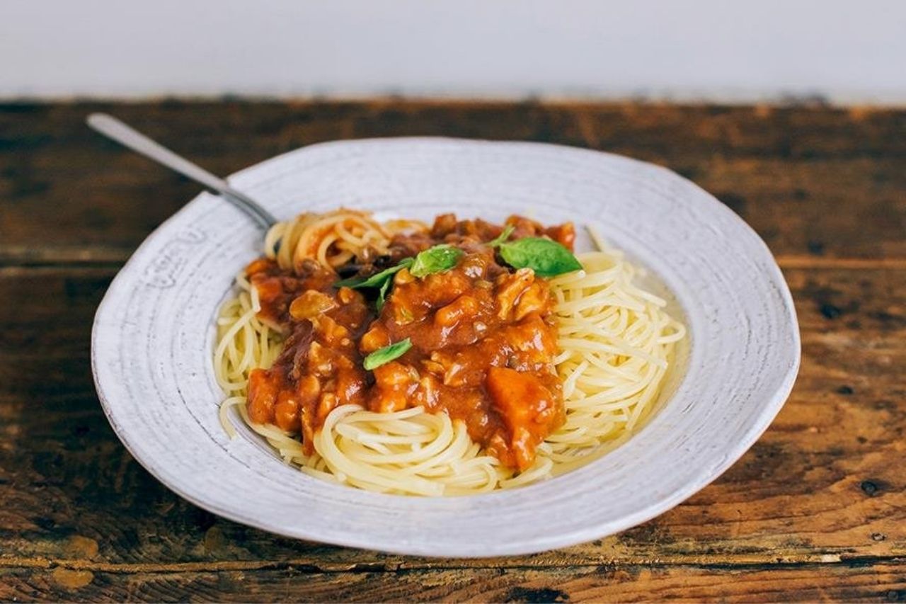 A plate of vegan spaghetti bolognese topped with fresh basil