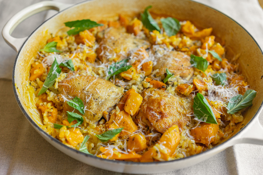 A pan with seared chicken thighs and squash risotto