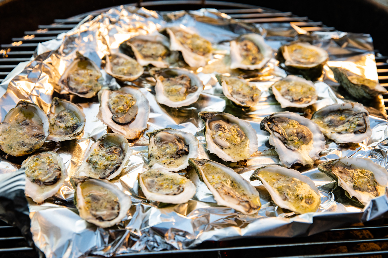 Grilled oysters on the half shell placed on a foil-topped grill