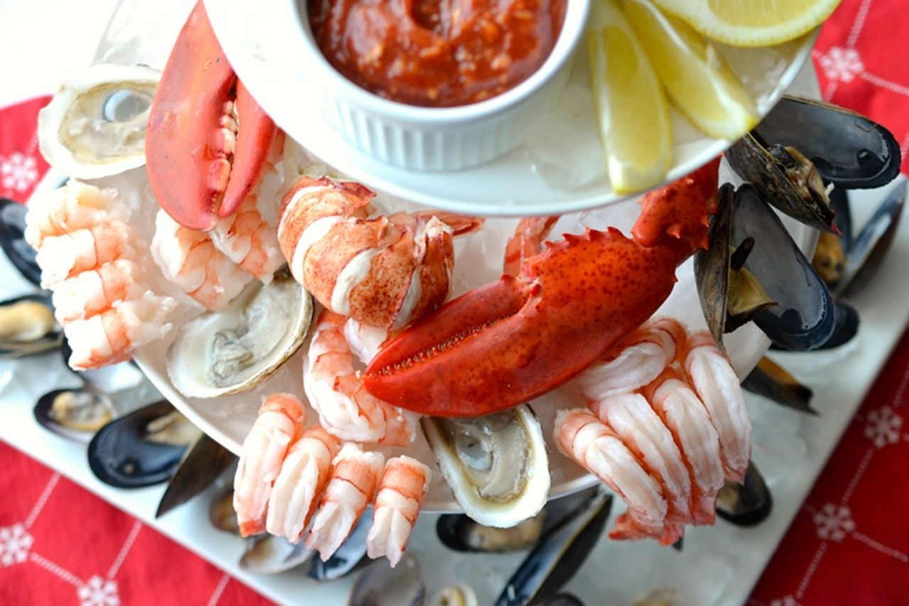 Seafood lobster tower with cocktail sauce, lemons and shrimp and oysters on a white tower