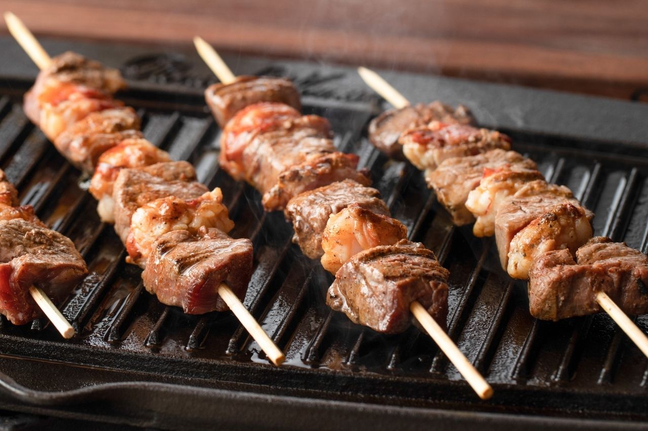 Beef and lobster skewers on a grill