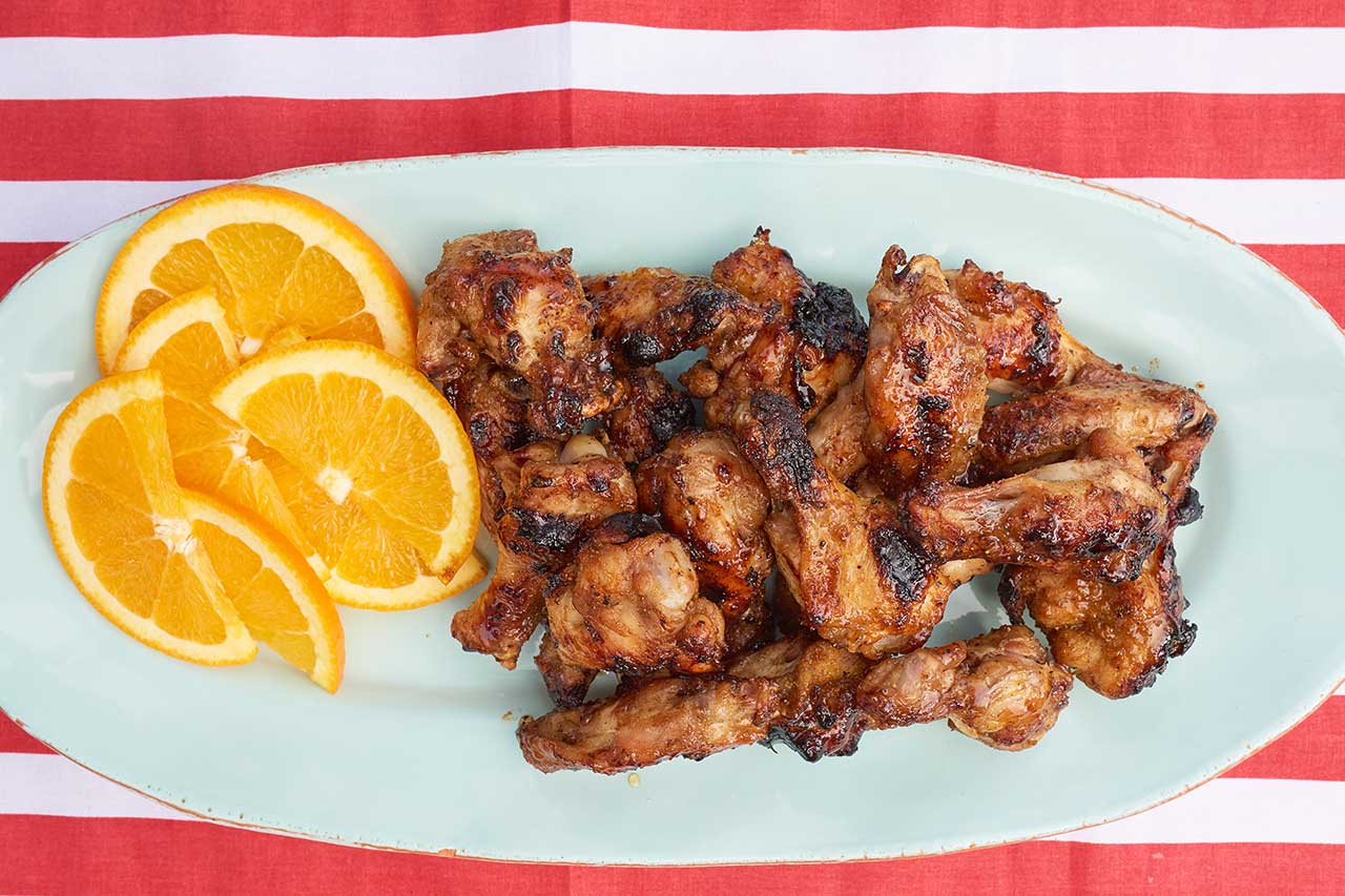 chicken wings on a green plate with orange slices