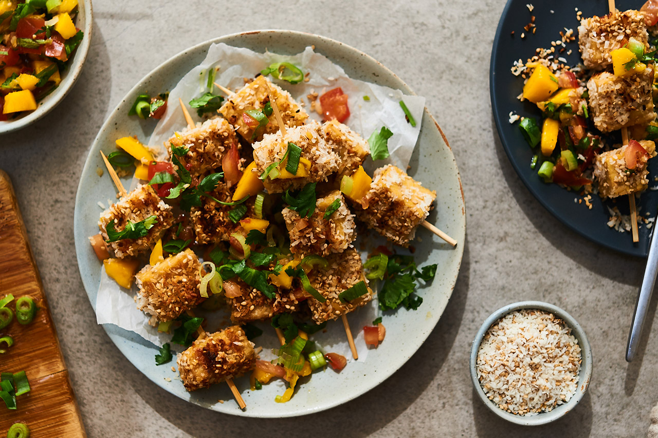A plate of crunch tempeh skewers with fresh mango and herbs