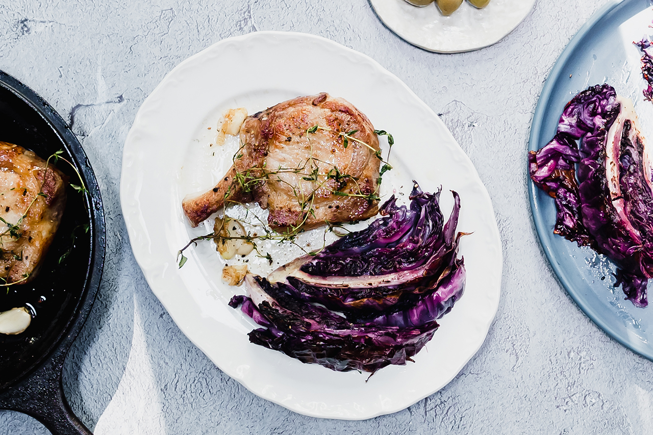 Pan-fried pork chops and roasted cabbage on white plate