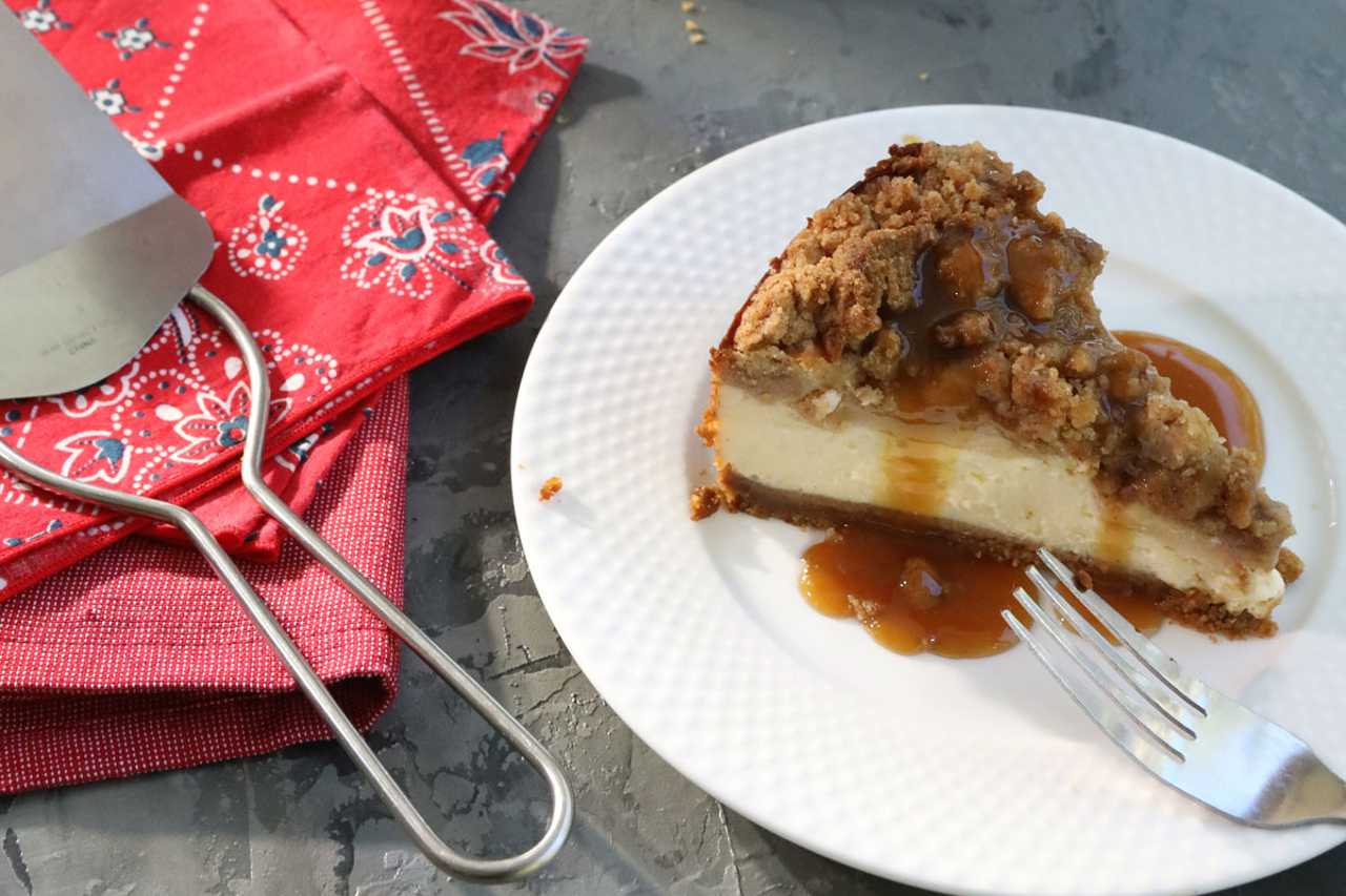 A slice of apple cheesecake with caramel frizzle on a plate