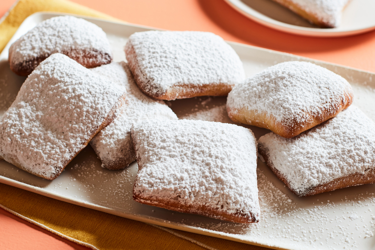 Powdered sugar dusted air fryer beignets on a white serving dish