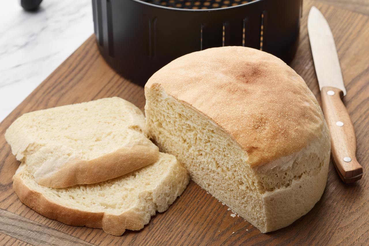 A loaf of air fryer bread on a cutting board with two slices cut from it