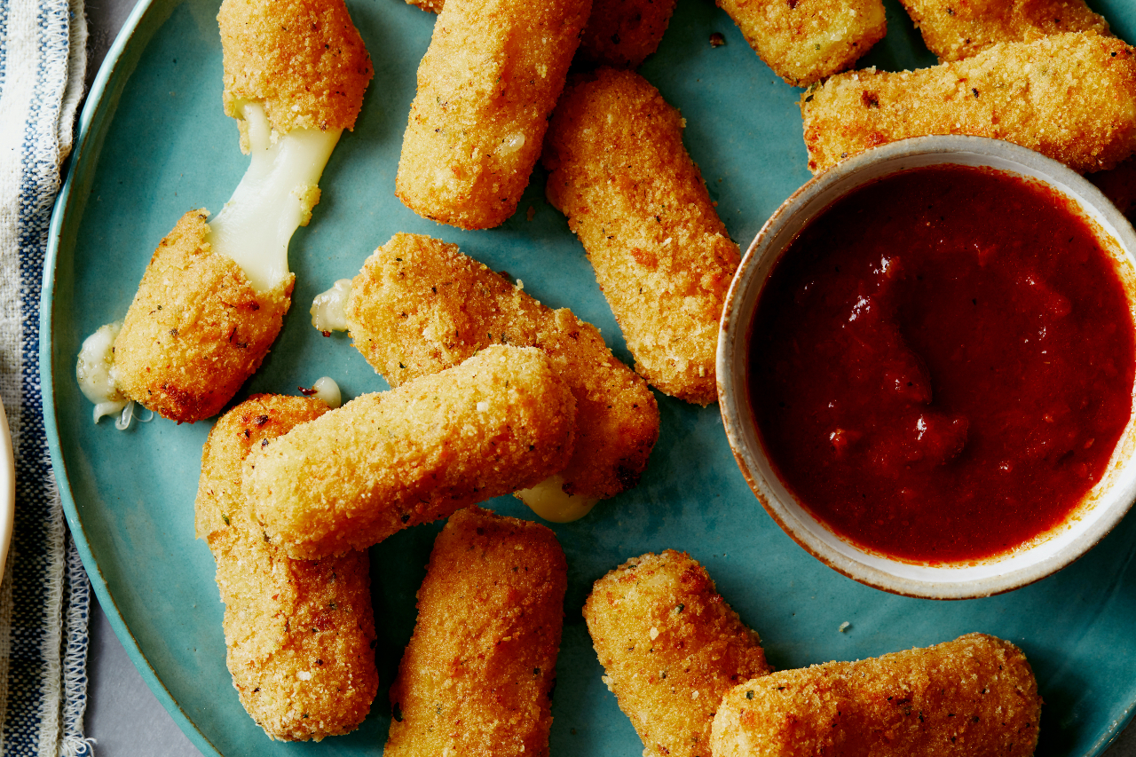 Air fryer ranch mozzarella sticks on a turquoise plate with a bowl of dipping sauce