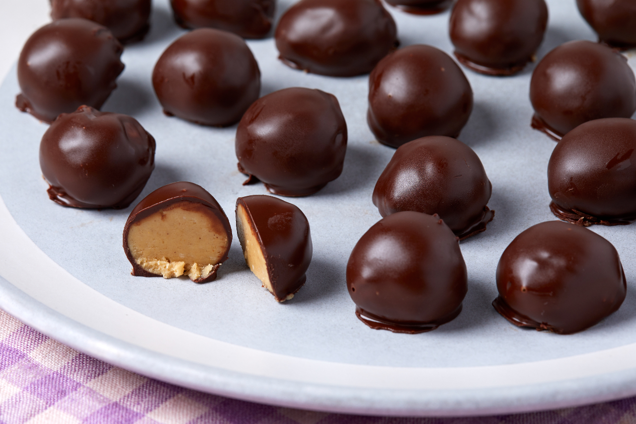 Chocolate coated peanut butter balls on a white serving tray