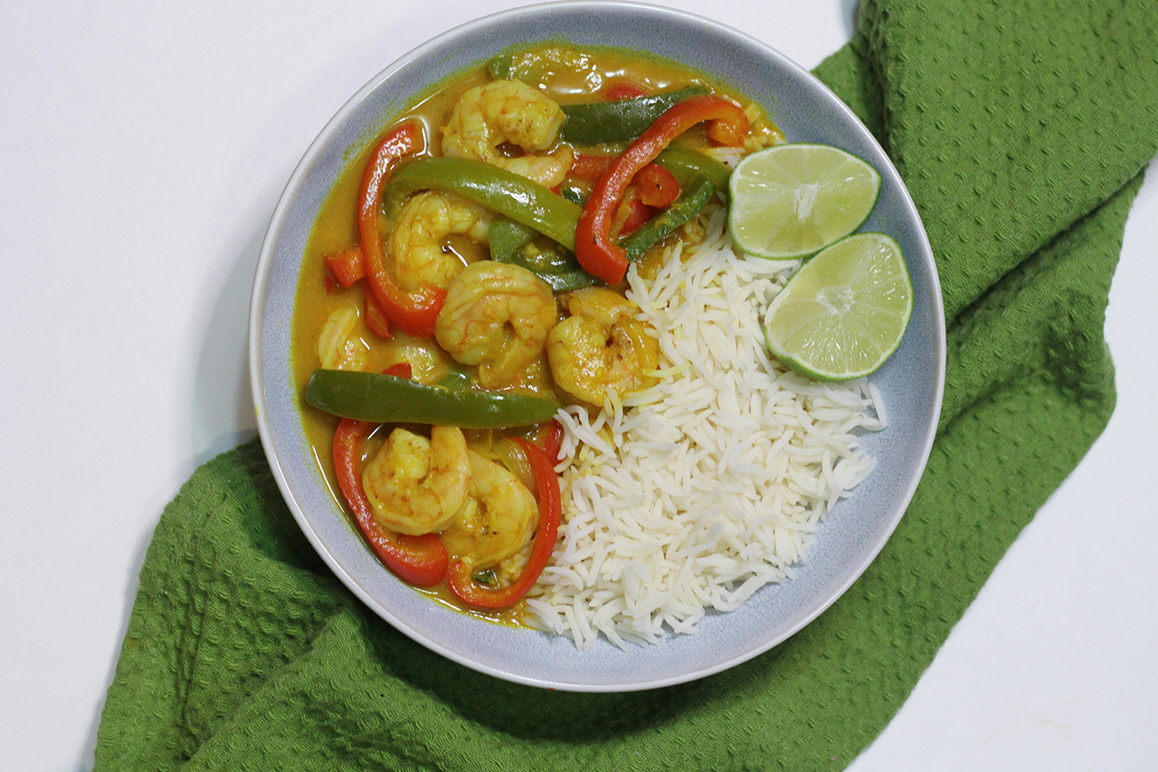 Curry shrimp and rice in white bowl on top of green tea towel