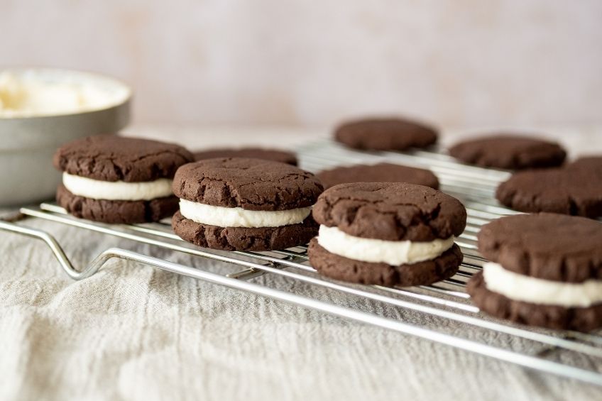 A close up of four creme-stuffed chocolate cookie sandwiches on a silver baking tray