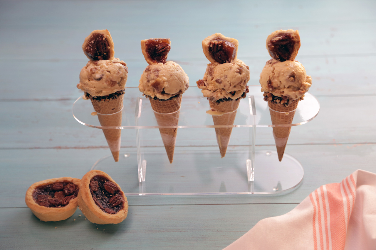 Four cones with butter tart ice cream, each topped with a quarter of a butter tart