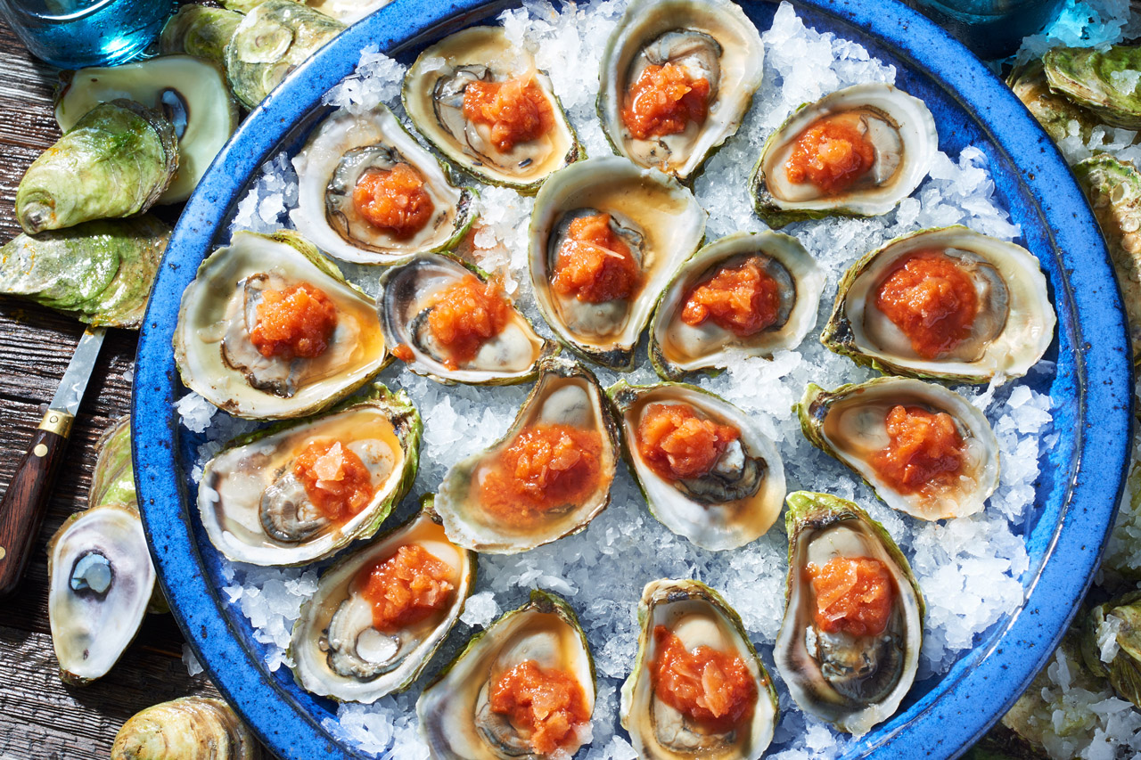A platter of oysters topped with a spicy tomato ice