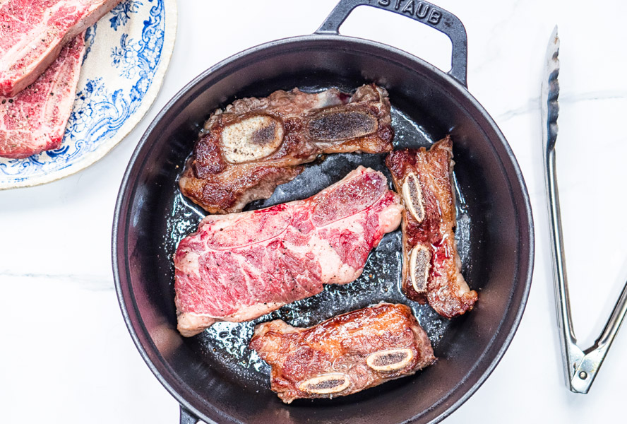 short ribs being seared in a dutch oven