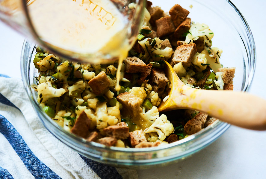 Mixing keto-style cauliflower stuffing ingredients in a bowl