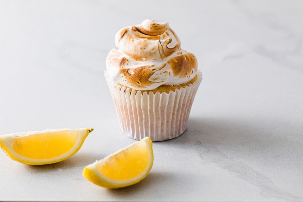 Lemon meringue cupcake with a few slices of lemon beside it