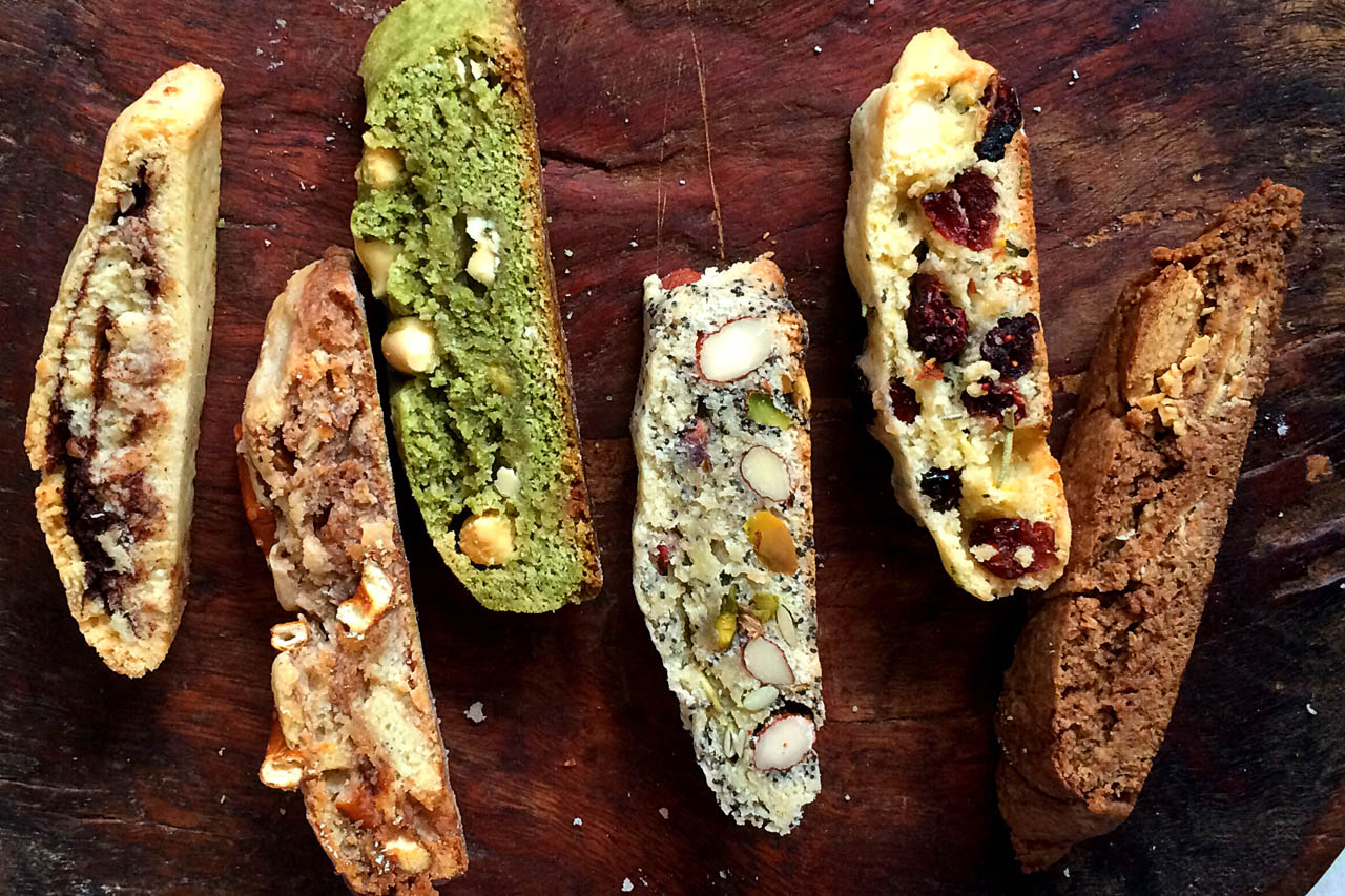 6 different types of biscotti on a dark wood tabletop