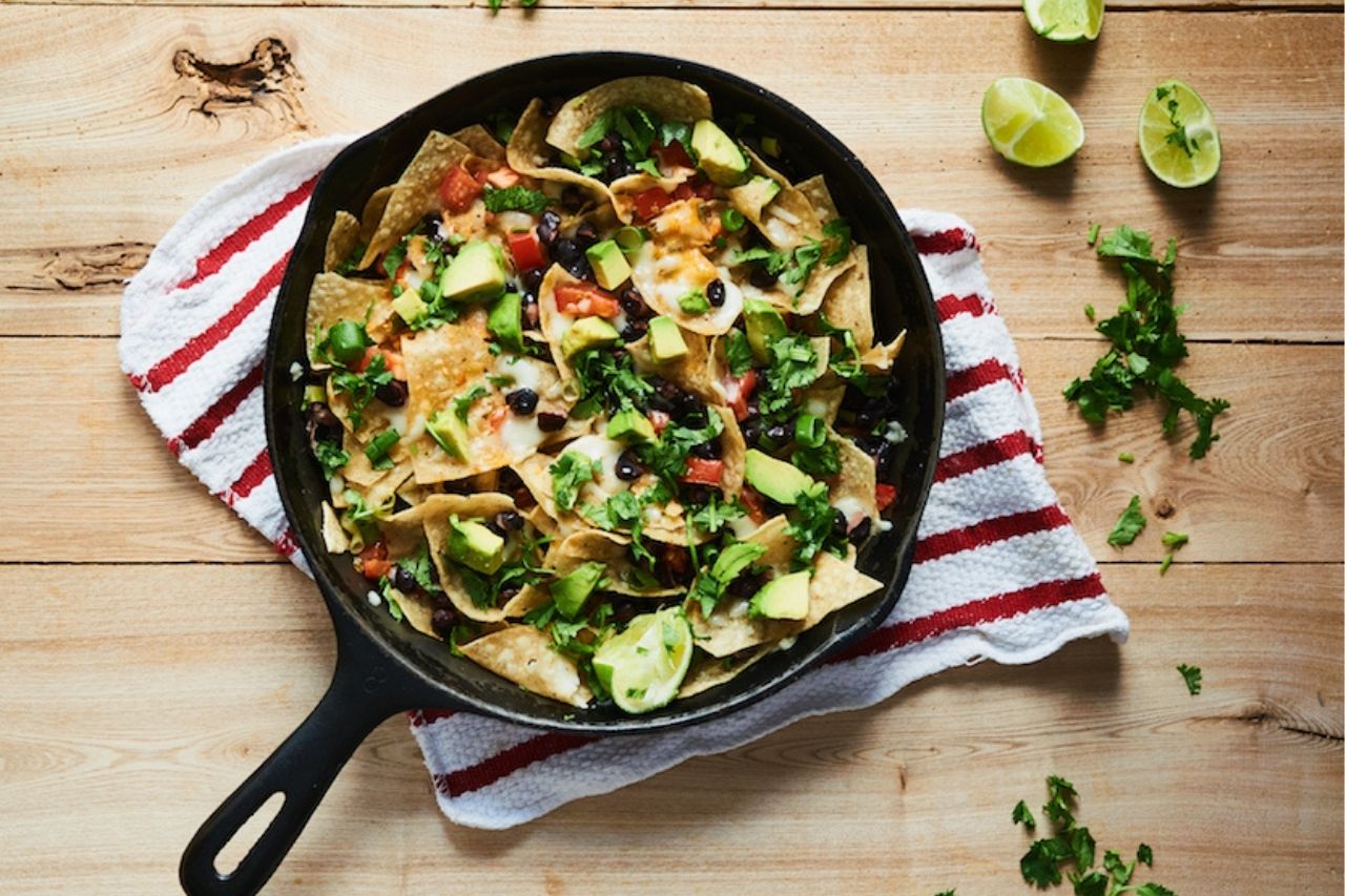 Overhead shot of a skillet of nachos on a red and white striped table cloth