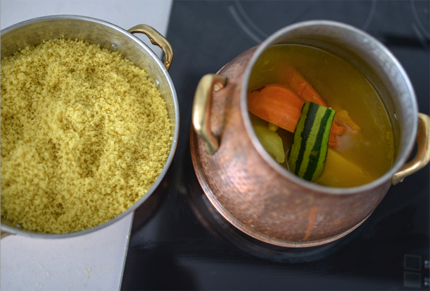 Couscous in a colander beside a pot of soup